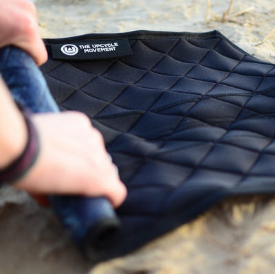 A pair of hands rolling a neoprene changing mat on the ground